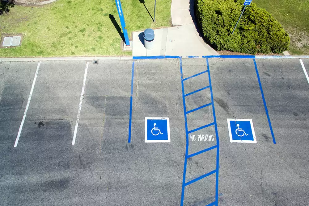 Standard ADA signage and designated accessible parking spots at the front of a parking lot.