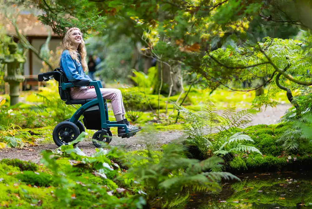 A woman in a power wheelchair sits on an accessible path.