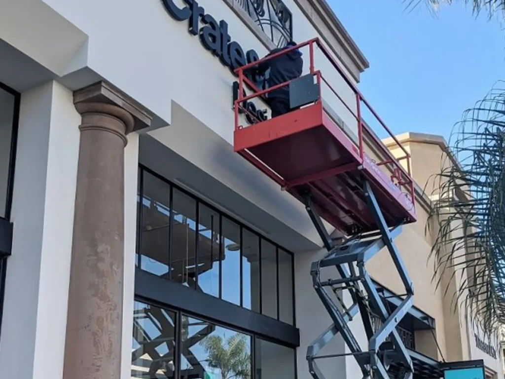 man installing a outdoor sign using a lift