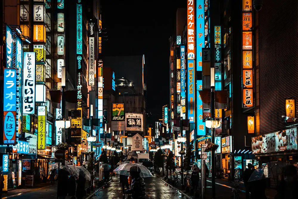 A busy Tokyo street at night that glows under dozens of illuminated signs